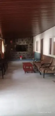 a living room with two benches and a stone fireplace at Varshinicottage kothkiri in Kotagiri