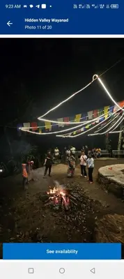 a group of people standing around a fire at night at Wooden creek tent camping in Meppādi