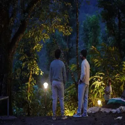 two men standing in a forest at night at Wooden creek tent camping in Meppādi