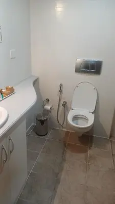 a white bathroom with a toilet and a sink at Hotel Grand Regency, Angamaly in Angamali