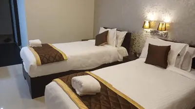 a hotel room with two beds and two lamps at Hotel Grand Regency, Angamaly in Angamali