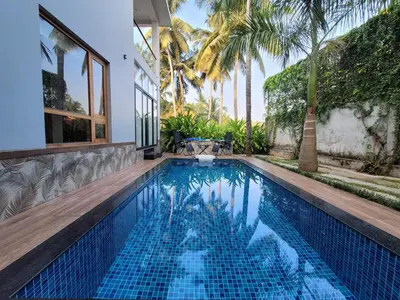 a swimming pool in a villa with palm trees at Aurora The Pool Villa ll in Kozhikode