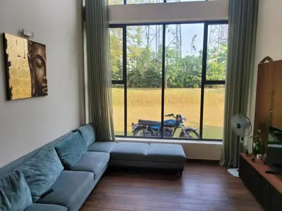 a living room with a blue couch in front of a window at Aurora The Pool Villa ll in Kozhikode