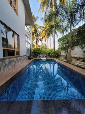 a swimming pool in the backyard of a house with palm trees at Aurora The Pool Villa ll in Kozhikode