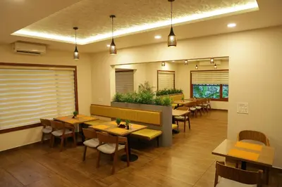 a restaurant with tables and chairs in a room at Hortus Malabaricus Garden Resort in Cheruthuruthi