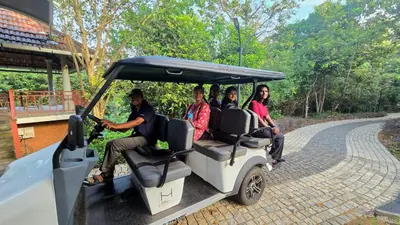 a group of people riding in a golf cart on a road at Hortus Malabaricus Garden Resort in Cheruthuruthi