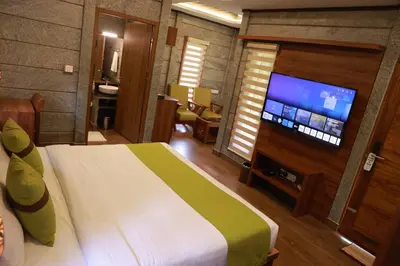 a bedroom with a bed and a flat screen tv at Hortus Malabaricus Garden Resort in Cheruthuruthi