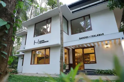 a white house with black windows at Hortus Malabaricus Garden Resort in Cheruthuruthi