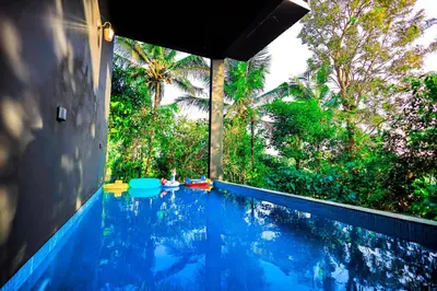 a blue swimming pool with trees in the background at La Vista Resorts in Wayanad