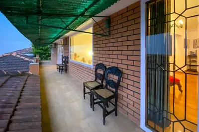 a couple of chairs sitting on the porch of a house at Away From Home - 2 - Home Stay Ooty, Entire 4BHK Villa in Ooty
