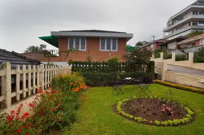 a garden in front of a house with a fence at Away From Home - 2 - Home Stay Ooty, Entire 4BHK Villa in Ooty