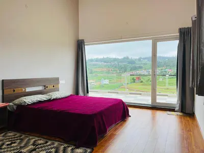 a bedroom with a bed and a large window at Away From Home - 3 - HomeStay Ooty, Entire 3BHK Villa in Ooty
