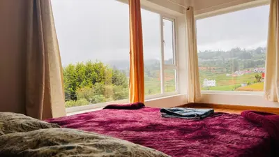 a bed in a room with a large window at Away From Home - 3 - HomeStay Ooty, Entire 3BHK Villa in Ooty