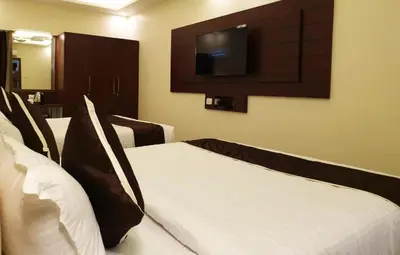 a hotel room with two beds and a flat screen tv at Hotel Saran Palani in Palani