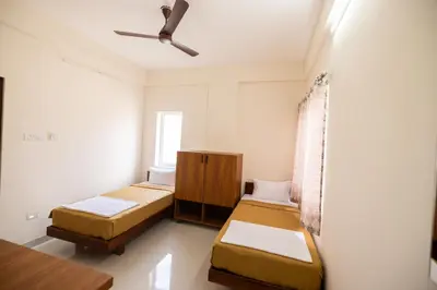 a bedroom with two beds and a ceiling fan at Viba Residency in Coimbatore