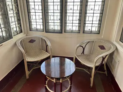 two chairs and a table in a room with windows at Heart of Mysore - Entire Place for yourself in Mysore