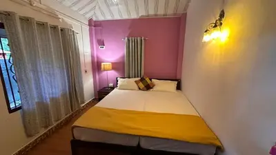 a small bed in a room with pink and yellow at Little Bricks Reverside Private Pool Villa by GreenEscapes in Vythiri