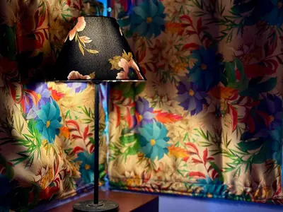 a lamp sitting on a table in a room with a flower wallpaper at Little Bricks Reverside Private Pool Villa by GreenEscapes in Vythiri