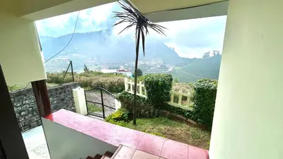a view from a balcony of a house with a palm tree at Away From Home - 1 - Rooms In Ooty, Home Stay Ooty in Ooty