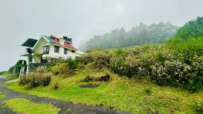 a house on the side of a grassy hill at Away From Home - 1 - Rooms In Ooty, Home Stay Ooty in Ooty