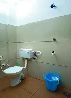 a bathroom with a toilet and a blue bucket at Hr residency in Kozhikode