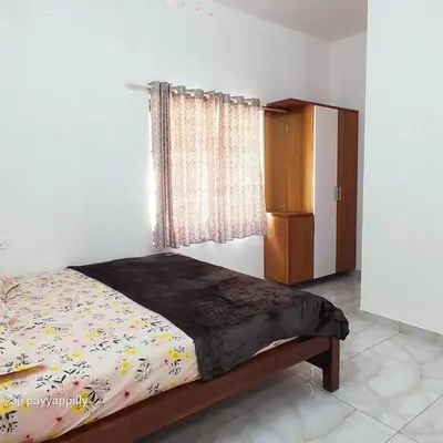 a bedroom with a bed and a cabinet and a window at Karukutty Rental House in Adūr