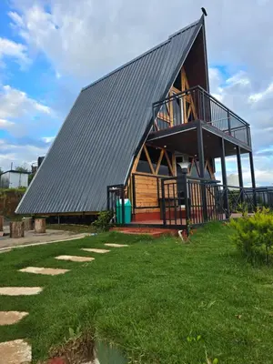 a large house with a gambrel roof on a lawn at Fairyland Resort in Kodaikānāl