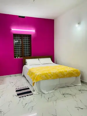 a bedroom with a large bed and a pink wall at In-woods stay in Olavakod Junction