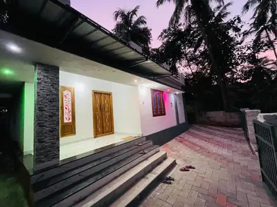 a small white house with a porch and a door at In-woods stay in Olavakod Junction