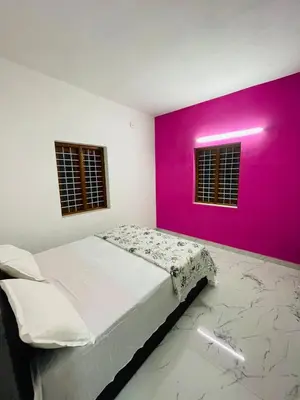 a bedroom with a bed with a pink wall at In-woods stay in Olavakod Junction