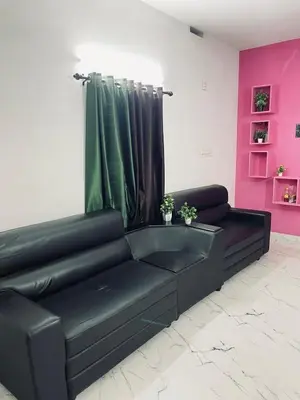 a black leather couch in a room with pink at In-woods stay in Olavakod Junction
