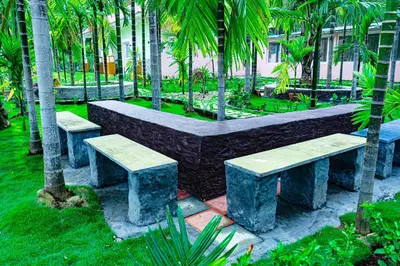 a row of stone benches in a park with palm trees at Galaxy Garden Resort in Kallār