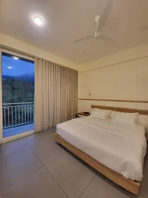 a bedroom with a large bed and a large window at Mountain Serenity Meppadi, Wayanad in Kalpetta