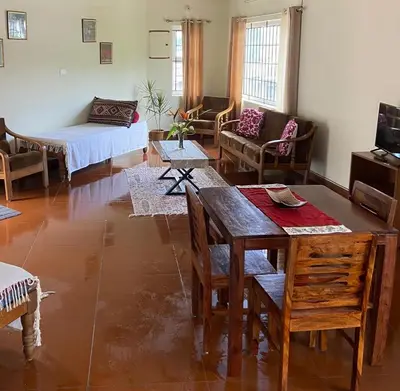 a living room with a table and chairs and a bed at Pristine Stay by LexStays in Coonoor