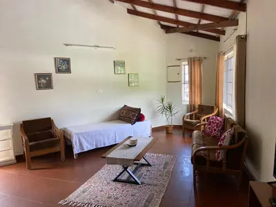 a living room with a bed and two chairs and a table at Pristine Stay by LexStays in Coonoor