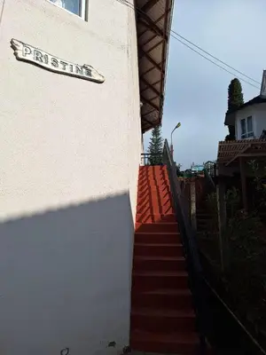 a sign on the side of a building with stairs at Pristine Stay by LexStays in Coonoor
