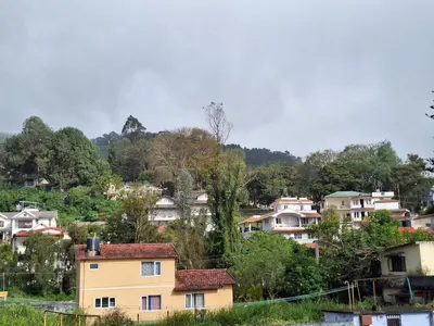 a group of houses on a hill with trees at Pristine Stay by LexStays in Coonoor