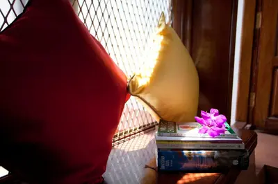 a table with a pillow and a book and flowers at The Blue Mountains Estate Stay in Madikeri