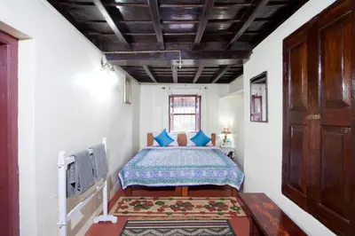 a bedroom with a bed with blue pillows at The Blue Mountains Estate Stay in Madikeri