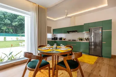 a kitchen with green cabinets and a table and chairs at Le Jardin - Luxury Private Pool Villa near Kochi, Kerala in Ernakulam