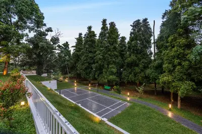 a tennis court in a park with trees and lights at Le Jardin - Luxury Private Pool Villa near Kochi, Kerala in Ernakulam