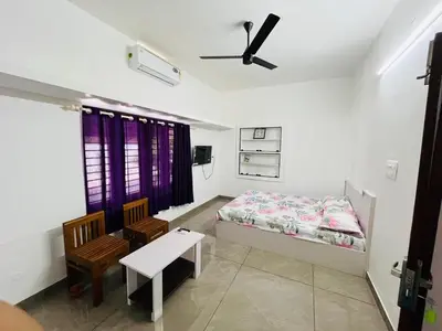 a bedroom with a bed and a table and chairs at Aagneyam mansion in Kozhikode