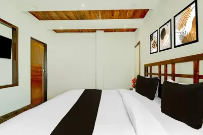 a bedroom with a large white bed with black pillows at Super Collection O Charing Cross Ooty in Ooty