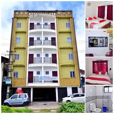 a yellow building with cars parked in front of it at Shanthala Residency in Virajpet