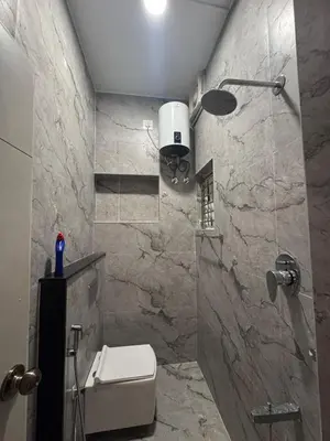 a bathroom with a toilet and a stone wall at Vels Villa A home away from home at Pollachi in Pollāchi