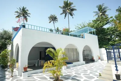 a white house with palm trees in the background at Voitto Vista in Cochin