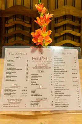 a menu on a table with a vase of flowers at Stella Marries Airpot Lounge in Nedumbassery