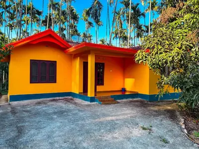 a yellow house with a red roof at Palm Resort in Gūdalūr