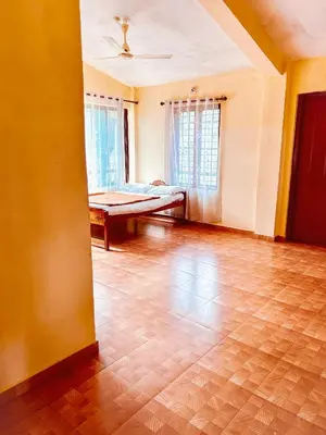 a living room with a wooden floor and a couch at Palm Resort in Gūdalūr