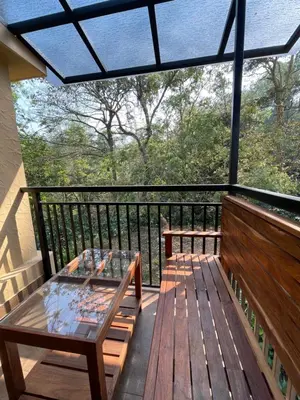 a screened in porch with a glass table on a deck at CASTELLO Holiday Villa in Kalpetta